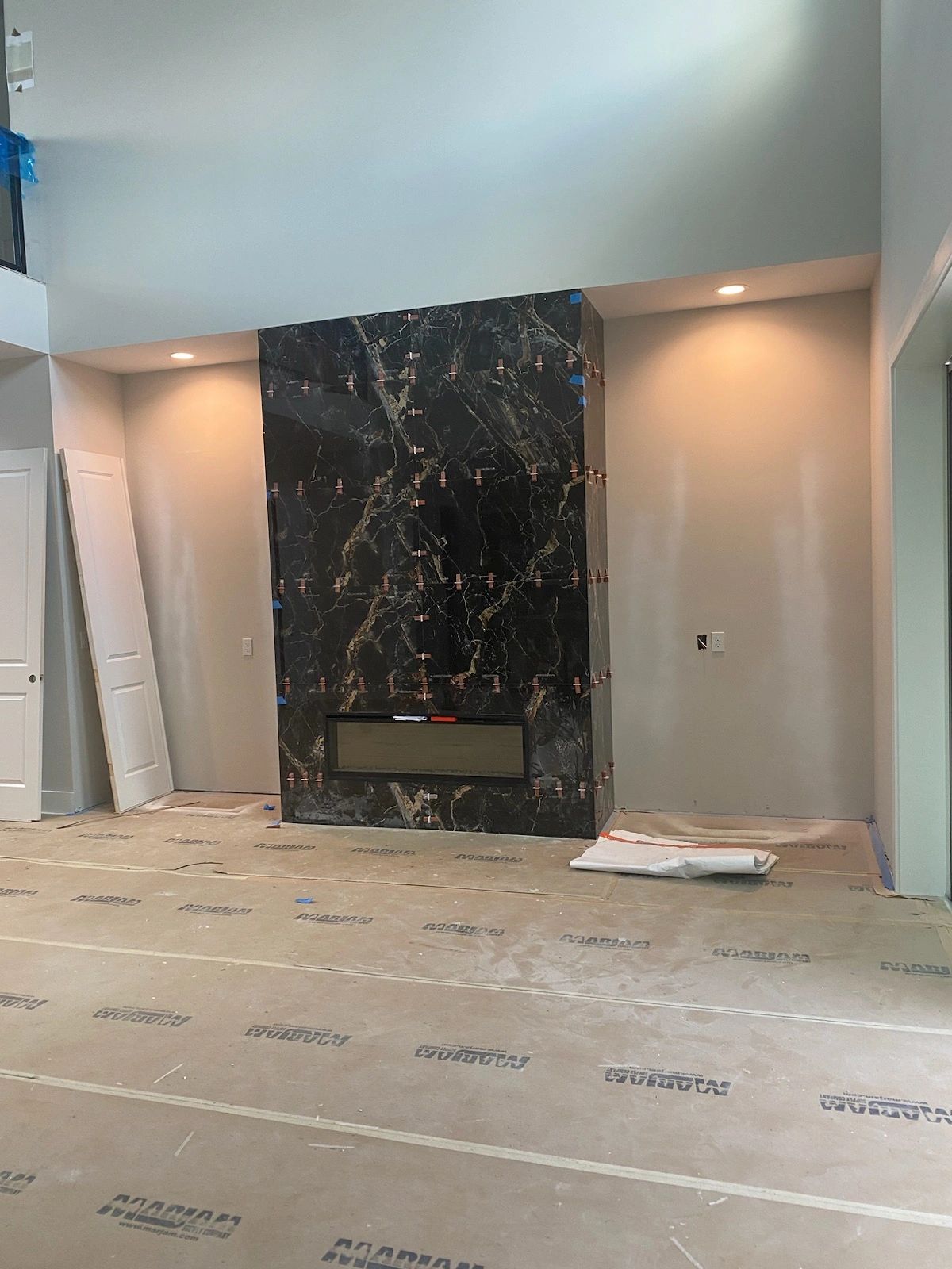Tile fireplace surround during installation, with tile spacers and protective floor covering